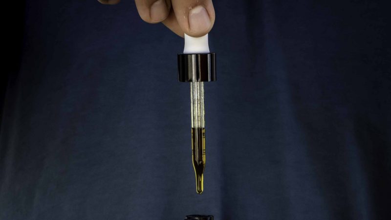 cbd oil dropper held by a person's hand