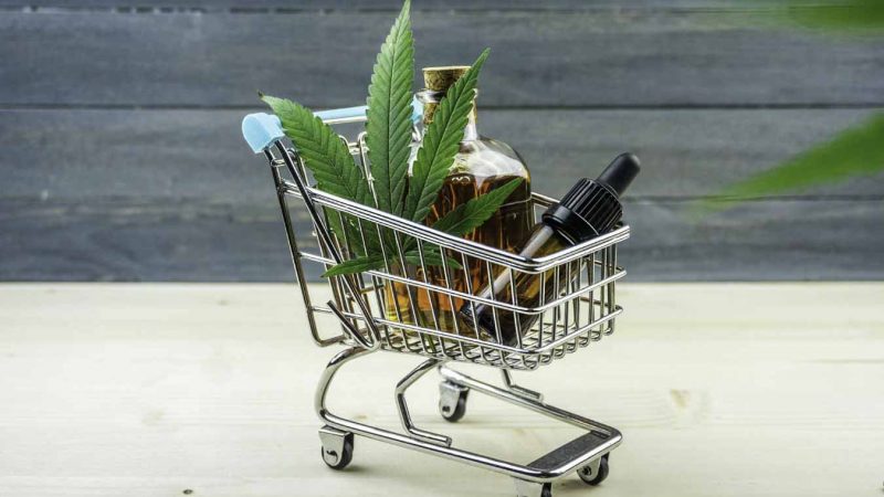 cbd oil products and a hemp leave on a tiny cart