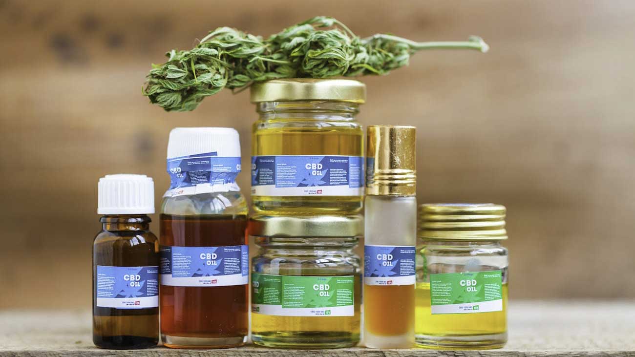 Image of CBD products and hemp bud on top of each other on a wooden table