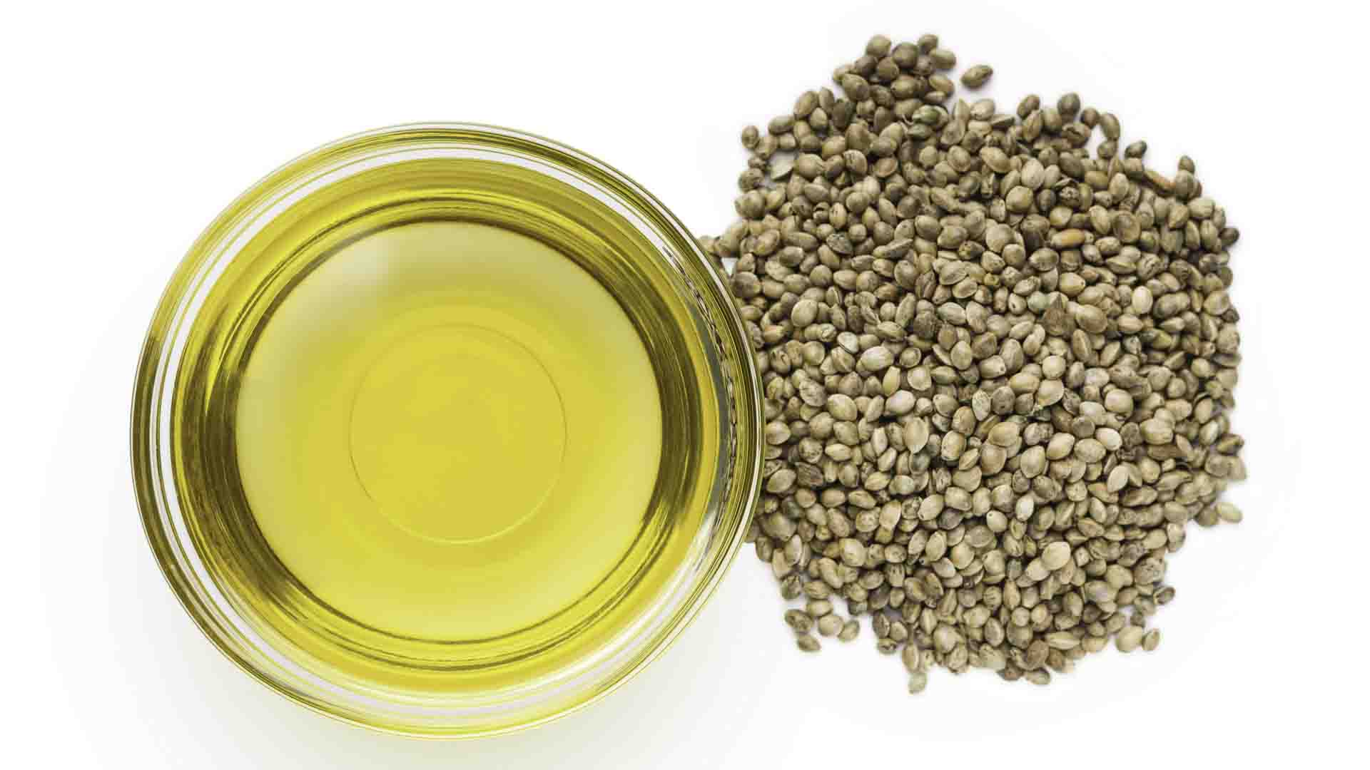 Hemp oil inside a glass bowl with hemp seed on the side in pure white background