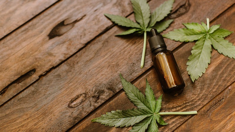 cbd oil and hemp leaf on a wooden table