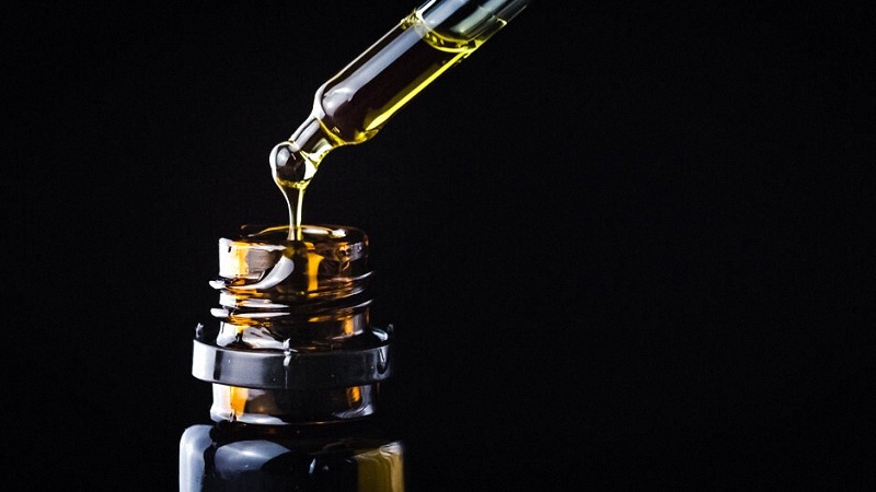 CBD Oil Dropping by Black Bottle