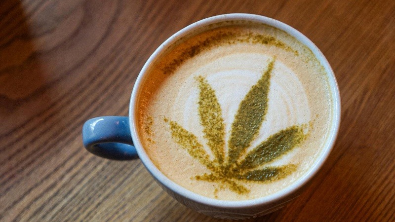 a cup of coffee with hemp leaf design on top