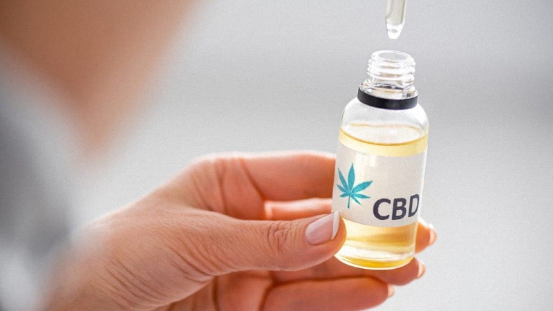 Hands Holding CBD Oil in Bottle with CBD Label