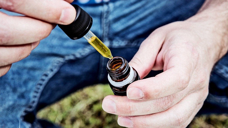 a man holding CDB oil and dropper about to take it