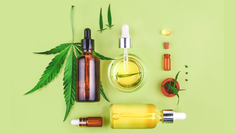 CBD oil in bottles with hemp leaf in a yellow green background