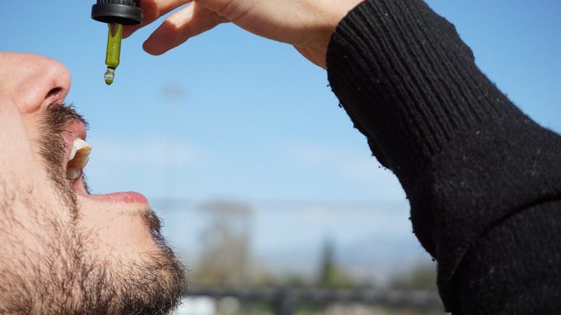 A Man in Black Sleeve Taking CBD Oil