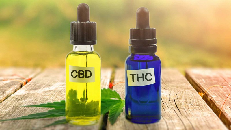 CBD Oil and THC Oil in Bottle with Hemp Lead on a Wooden Surface