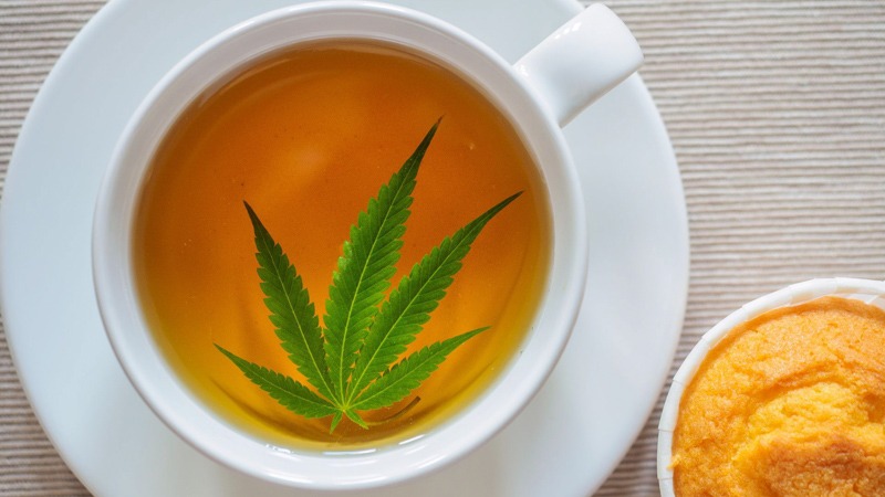 Hemp Leaf on Tea Placed in White Cup and Saucer Beside a Muffin