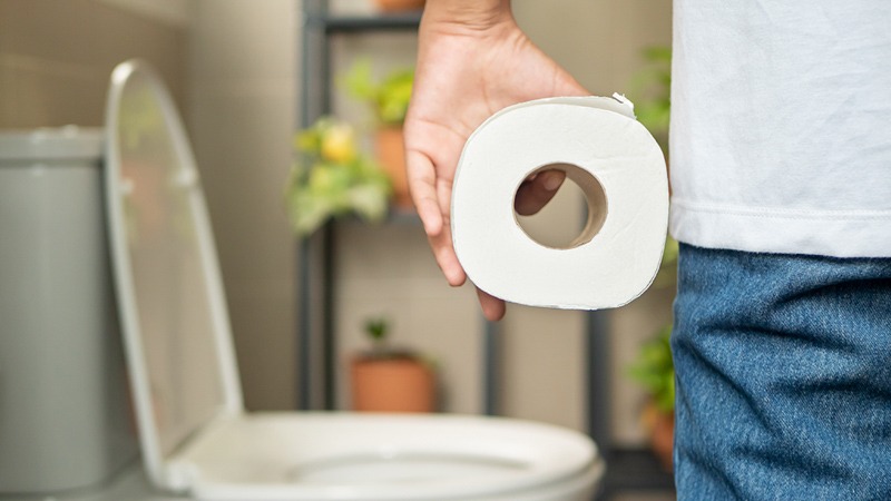 Person Holding a Tissue in a Toilet