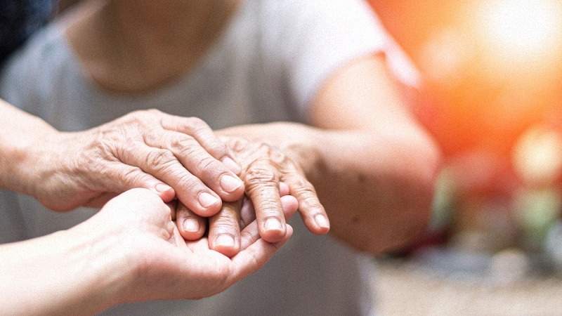 A doctor physician hand on an elderly senior with Parkinson's Disease