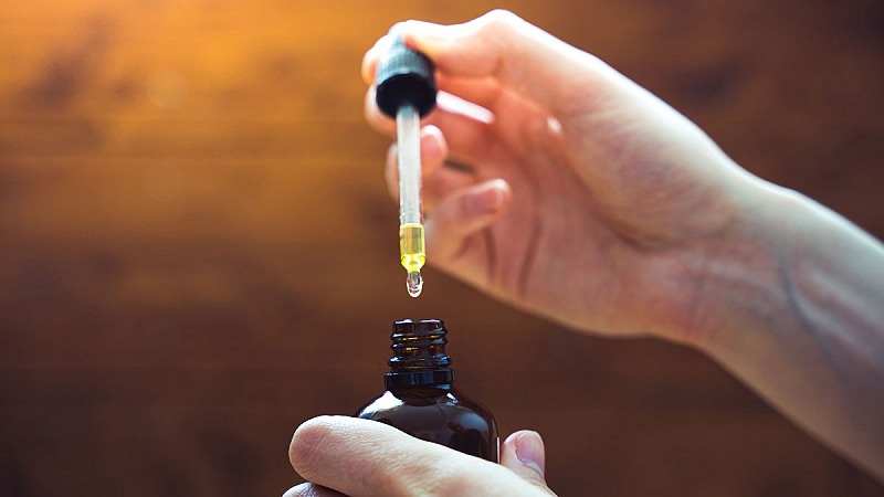 a hand taking cbd oil from a bottle