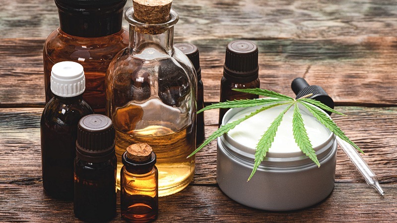 Cannabidiol extract in bottles a dropper and a topical cream with a hemp leaf on top