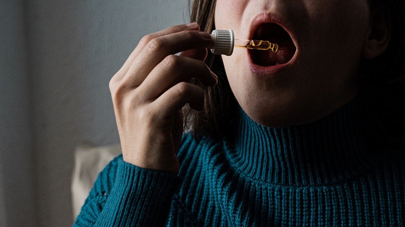 a woman taking CBD oil under tongue
