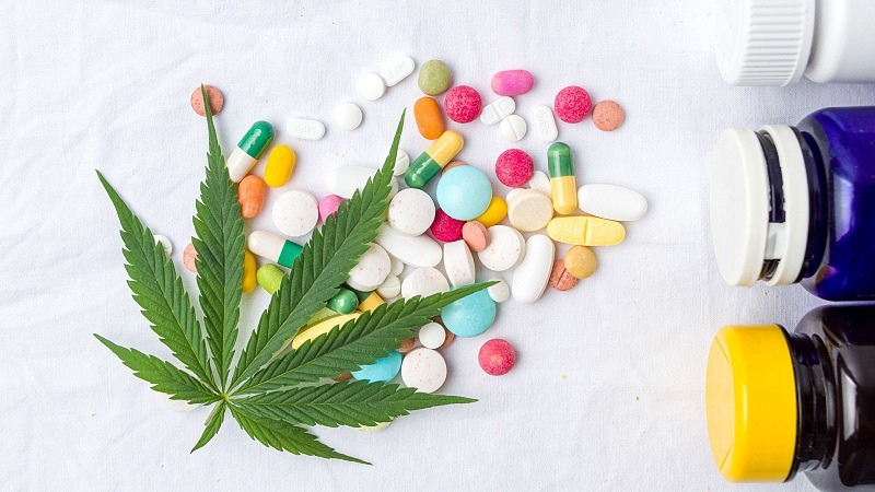 different tablets with a hemp leaf on top and bottles of medicines on a white background